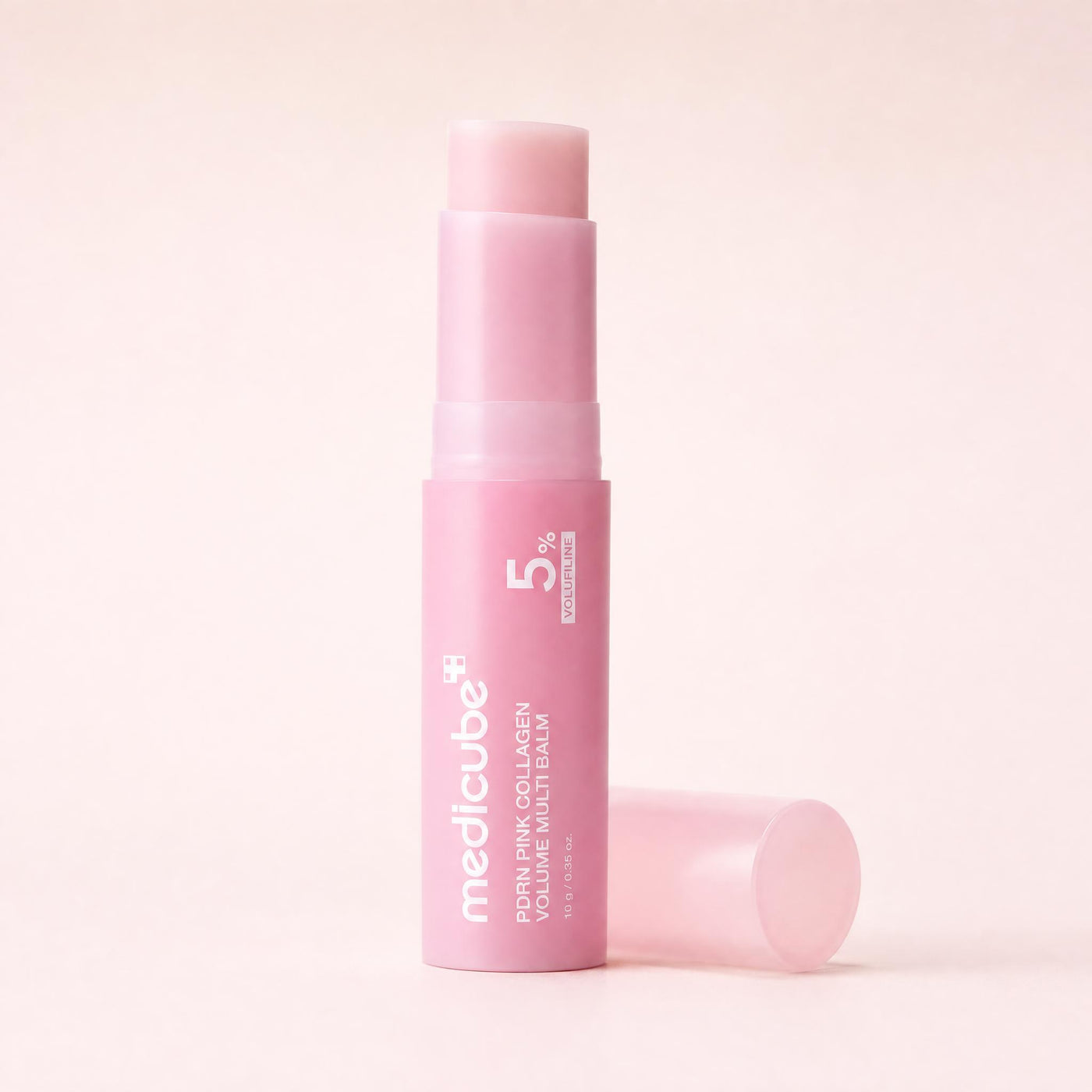 The balm stick with the cap removed, showing the pink balm dome