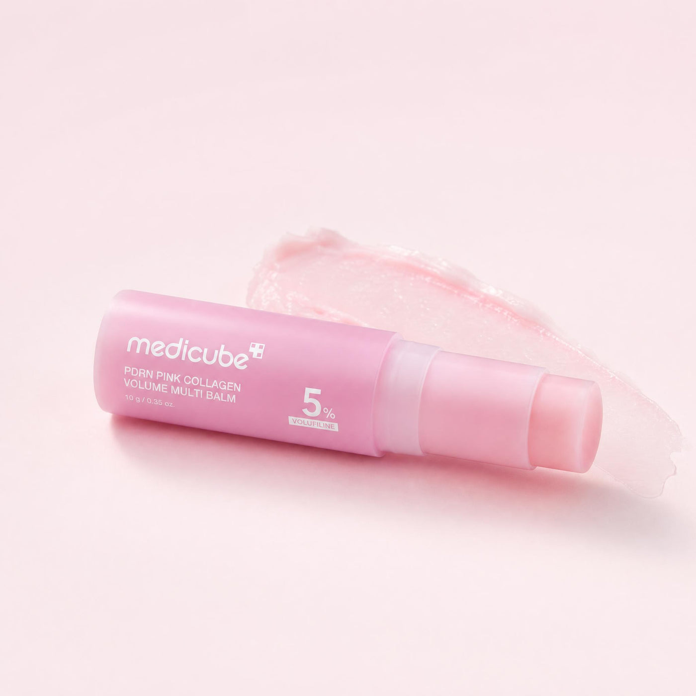 The balm stick lying beside a swipe of its pink balm texture