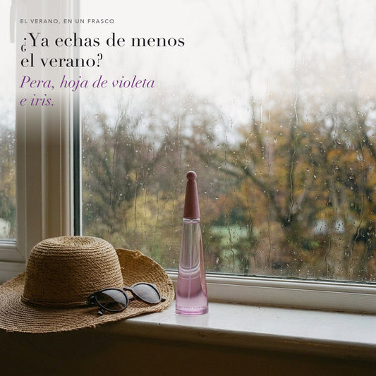 L'Eau d'Issey Solar Violet en una ventana con lluvia, junto a un sombrero de paja y unas gafas de sol