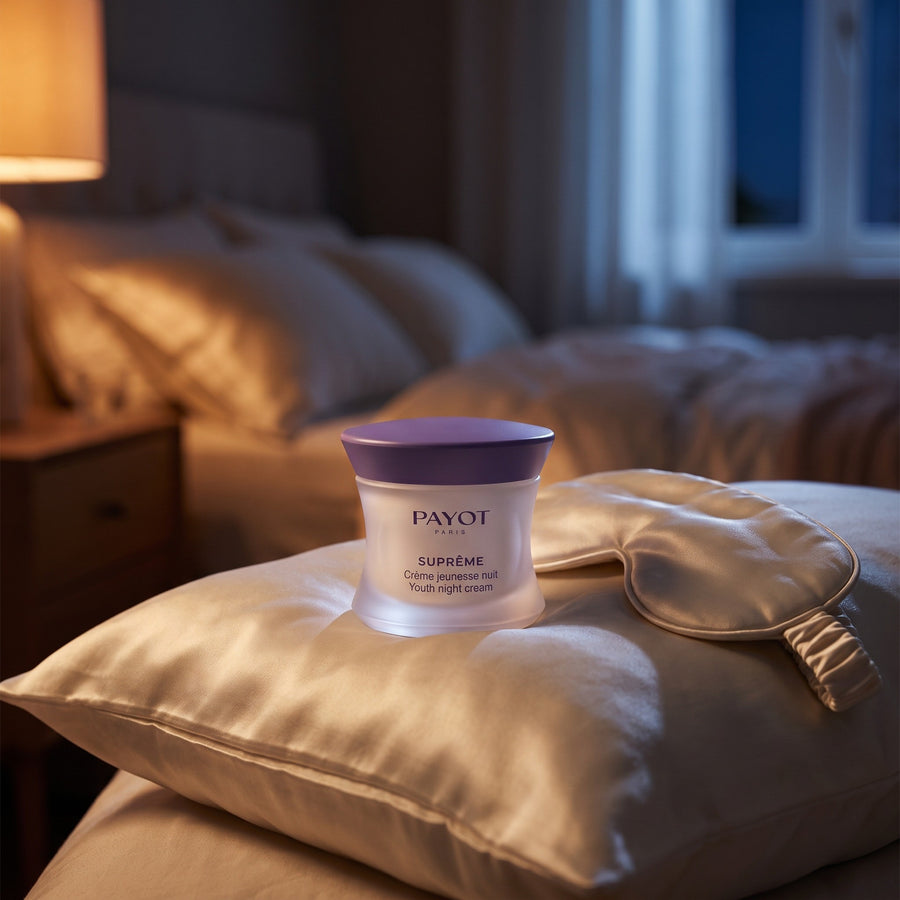 Crema de noche Payot Suprême en la mesilla, con luz cálida de lámpara